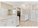Modern bathroom with dual sinks, white cabinetry, a glass-enclosed shower, and a walk-in closet for ample storage at 21506 Snowy Orchid Ter, Land O Lakes, FL 34637