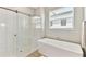 Bright bathroom featuring a modern tub with a sliding glass shower door, a rainfall shower head, and a built-in seat at 21506 Snowy Orchid Ter, Land O Lakes, FL 34637