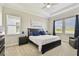 Cozy bedroom features a king-sized bed with navy blue accents, complemented by dual windows and an armchair at 21506 Snowy Orchid Ter, Land O Lakes, FL 34637