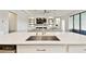 Kitchen island with steel sink features an open floor plan to living room with built-in bookshelves at 21506 Snowy Orchid Ter, Land O Lakes, FL 34637