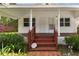 Inviting covered front porch with decorative railing and brick landing, surrounded by shrubs at 2231 Nichols Rd, Lithia, FL 33547