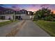 Charming townhome featuring a gray exterior, dark shutters, well-manicured lawn, and two-car garage at dusk at 23378 Papyrus Way, Lutz, FL 33549