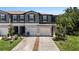 Charming townhome featuring a gray exterior, dark shutters, well-manicured lawn, and two-car garage at 23378 Papyrus Way, Lutz, FL 33549