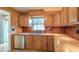 Traditional kitchen featuring wood cabinets, stainless steel dishwasher, and decorative tile backsplash at 31076 Castle Ridge Drive, Brooksville, FL 34602
