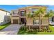 Inviting two-story home with a stone facade, tile roof, palm trees, and a paved driveway at 32324 Rosewood Meadow Ln, Wesley Chapel, FL 33543