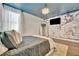 Inviting primary bedroom features unique mural art, blue ceilings, modern chandelier, and lots of natural light at 32324 Rosewood Meadow Ln, Wesley Chapel, FL 33543