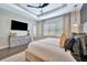 Comfortable bedroom featuring tray ceilings, hardwood floors, and a TV at 32324 Rosewood Meadow Ln, Wesley Chapel, FL 33543