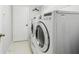 Modern laundry room equipped with a front-load washer and dryer, and a white door leading to other areas at 5119 Whispering Leaf Trail, Valrico, FL 33596