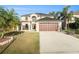 Two-story home with an attached two car garage, mature palm trees, and a well-manicured lawn at 5410 Treig Ln, Wesley Chapel, FL 33545