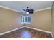 Cozy bedroom with wood floors, a ceiling fan, white trim, and a window with a peaceful outside view at 5449 Manatee Point Dr, New Port Richey, FL 34652