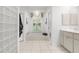 Bright bathroom with neutral tile, glass block partition, window, and well-lit vanity with lots of storage at 710 N River Rd, Venice, FL 34293