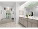Bright bathroom with neutral tile, glass block partition, window, and large well-lit dual sink vanity at 710 N River Rd, Venice, FL 34293