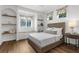 Comfortable bedroom features a bed, windows, floating shelves, and hardwood floors at 710 N River Rd, Venice, FL 34293
