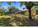 Rear exterior view of the home with a screened-in lanai area and lush green yard at 710 N River Rd, Venice, FL 34293