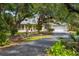 Charming home with mature trees, lush landscaping, a circular driveway, and a three-car garage at 710 N River Rd, Venice, FL 34293