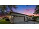 Well-maintained home with a two-car garage, driveway, and lush landscaping, set against a vibrant sunset at 7519 Berna Ln, Land O Lakes, FL 34637