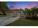 Lovely home with a two-car garage, concrete driveway, landscaping, and a beautiful evening sky at 7519 Berna Ln, Land O Lakes, FL 34637