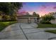 Charming single-story home with a two-car garage, driveway, and mature landscaping under a colorful sky at 7519 Berna Ln, Land O Lakes, FL 34637