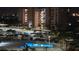 Night view of a building and pool area, with covered parking, and palm trees with festive lighting at 7700 Sun Island S Dr # 506, South Pasadena, FL 33707