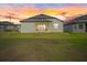 Home backyard with covered patio and green lawn at sunset at 1043 Davis Heather Cir, Seffner, FL 33584