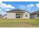 View of home's backyard showing a covered patio with chairs, sliding glass doors, and a well-maintained lawn at 1043 Davis Heather Cir, Seffner, FL 33584