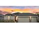 Charming single-story home featuring a 3-car garage, stone accents, and a beautiful sunset backdrop at 1043 Davis Heather Cir, Seffner, FL 33584