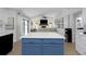 Kitchen island with blue cabinets and white countertop looks into the living room with fireplace and tv at 14007 Middleton Way, Tampa, FL 33624