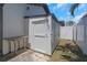 Exterior shed with white paint and a small table next to a white fence in backyard at 14007 Middleton Way, Tampa, FL 33624