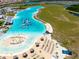 Community lagoon aerial showcasing splash park, sandy beach, lounging areas, and well maintained surrounding landscape at 16810 Trite Bend St, Wimauma, FL 33598