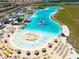 Aerial view of the lagoon with a sandy beach area, splash park, and plentiful lounge seating for residents at 16810 Trite Bend St, Wimauma, FL 33598