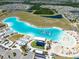 Aerial view shows the lagoon's clear water, beach, and inflatable structures at 16810 Trite Bend St, Wimauma, FL 33598