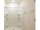 All-white bathroom shower stall with tiled walls and built-in shelving at 16810 Trite Bend St, Wimauma, FL 33598