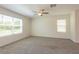 Bright and airy bedroom featuring carpet flooring, a ceiling fan, and two windows at 16810 Trite Bend St, Wimauma, FL 33598