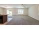 Expansive living room with abundant natural light, carpet flooring, and sliding glass doors to the backyard at 16810 Trite Bend St, Wimauma, FL 33598