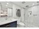 Elegant bathroom with marble walls, a glass-enclosed shower, and a navy blue vanity at 17940 Gulf Blvd # 9B, Redington Shores, FL 33708