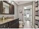 Bathroom featuring granite counters, wood cabinets, framed mirror and access to the laundry room and backyard at 18533 Avocet Dr, Lutz, FL 33558