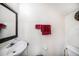Cozy bathroom featuring a pedestal sink, wall mirror, and a toilet with red decorative towels at 18981 Duquesne Dr, Tampa, FL 33647
