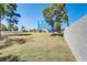 Large, grassy backyard featuring mature trees and a view of the bright blue home at 228 Shore Dr, Tarpon Springs, FL 34689