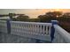 Balcony view showcasing a stunning sunrise over the water, framed by lush trees and a classic white railing with blue accents at 228 Shore Dr, Tarpon Springs, FL 34689