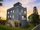 Striking blue home with a unique elevated design and lush landscaping at sunset at 228 Shore Dr, Tarpon Springs, FL 34689