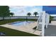 A modern in-ground pool with a sun shelf and seating set in a light gray tiled yard at 228 Shore Dr, Tarpon Springs, FL 34689