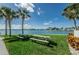 View of picnic benches in community area with lush landscaping and water in the background at 240 Sand Key Estates Dr # 58, Clearwater Beach, FL 33767