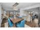 Open concept dining area with a wooden table, blue chairs, and views into a modern kitchen at 240 Sand Key Estates Dr # 58, Clearwater Beach, FL 33767