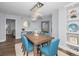 This stylish dining room is centered around a wooden table with blue chairs and a modern chandelier at 240 Sand Key Estates Dr # 58, Clearwater Beach, FL 33767