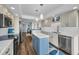 Bright kitchen featuring white cabinets, a blue island, and stainless steel appliances at 240 Sand Key Estates Dr # 58, Clearwater Beach, FL 33767