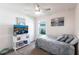 Bright bedroom featuring a ceiling fan, a TV set on a white cabinet, and coastal-themed decor at 25317 E Lenox Cir, Punta Gorda, FL 33950