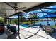 Screened-in pool area with a lake view, travertine flooring, comfortable seating, and lush landscaping at 25317 E Lenox Cir, Punta Gorda, FL 33950