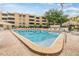 Outdoor pool with lounge chairs, lush landscaping, a tiki hut, and condo building in the background at 2616 Cove Cay Dr # 301, Clearwater, FL 33760