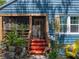 Cozy front porch with bright red stairs, potted plants, and a yellow chair, creating a warm and inviting entrance at 3001 9Th N Ave, St Petersburg, FL 33713
