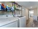 Laundry room equipped with modern washer and dryer, shelving for storage, and a view into the adjacent kitchen at 3112 65Th N Way, St Petersburg, FL 33710